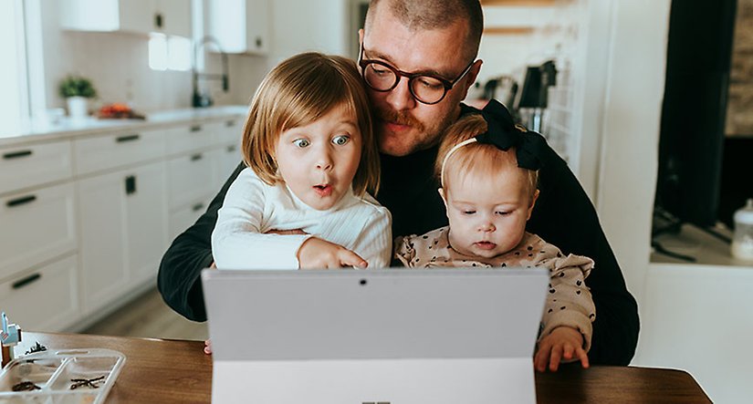 Pappa med barn framför en dator (Gratisbild från Unsplash)